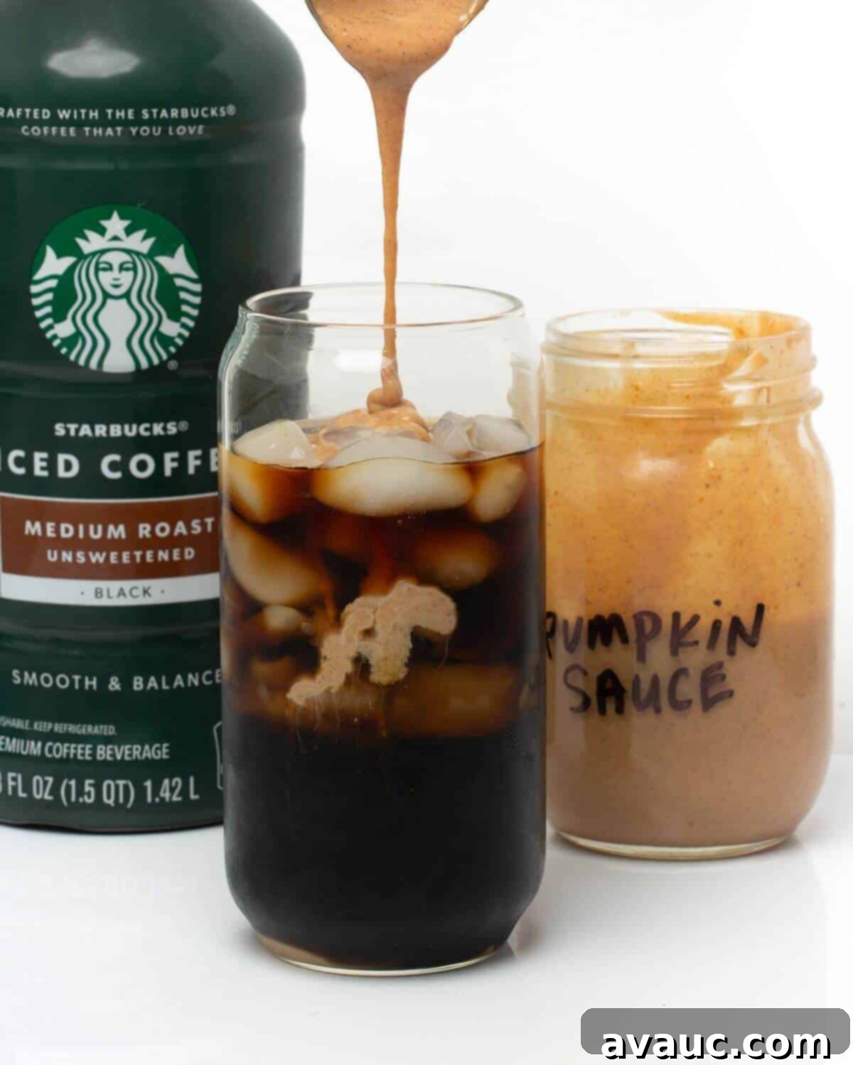 Handcrafted Pumpkin Spice Syrup 7 Pouring homemade pumpkin spice sauce into a glass of cold brew coffee, creating a swirling autumn beverage.