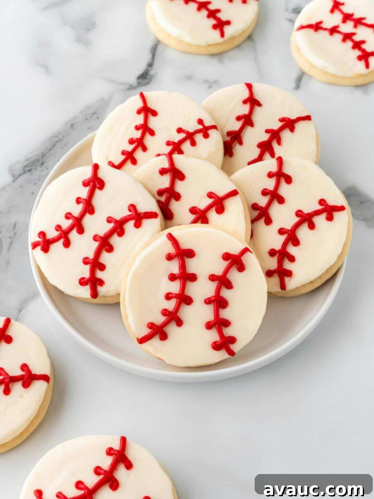 Perfectly frosted baseball sugar cookies arranged on a white glass plate