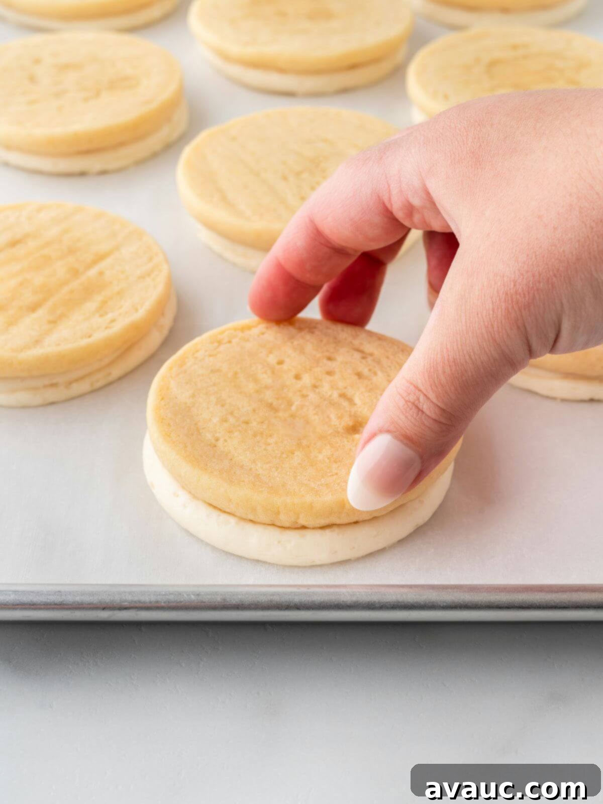 Frosted sugar cookie flipped upside down onto parchment paper to flatten the icing