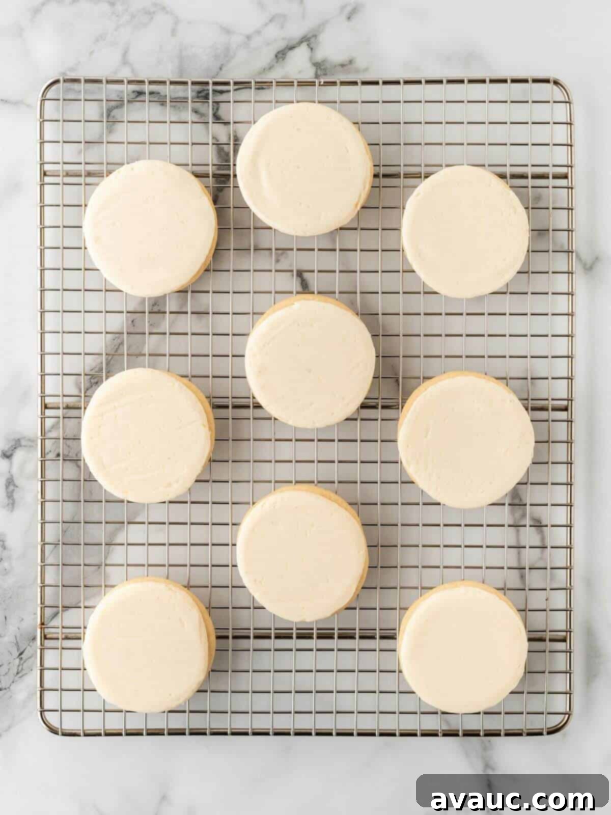A row of perfectly frosted sugar cookies on a cooling rack, ready for the next decorating step