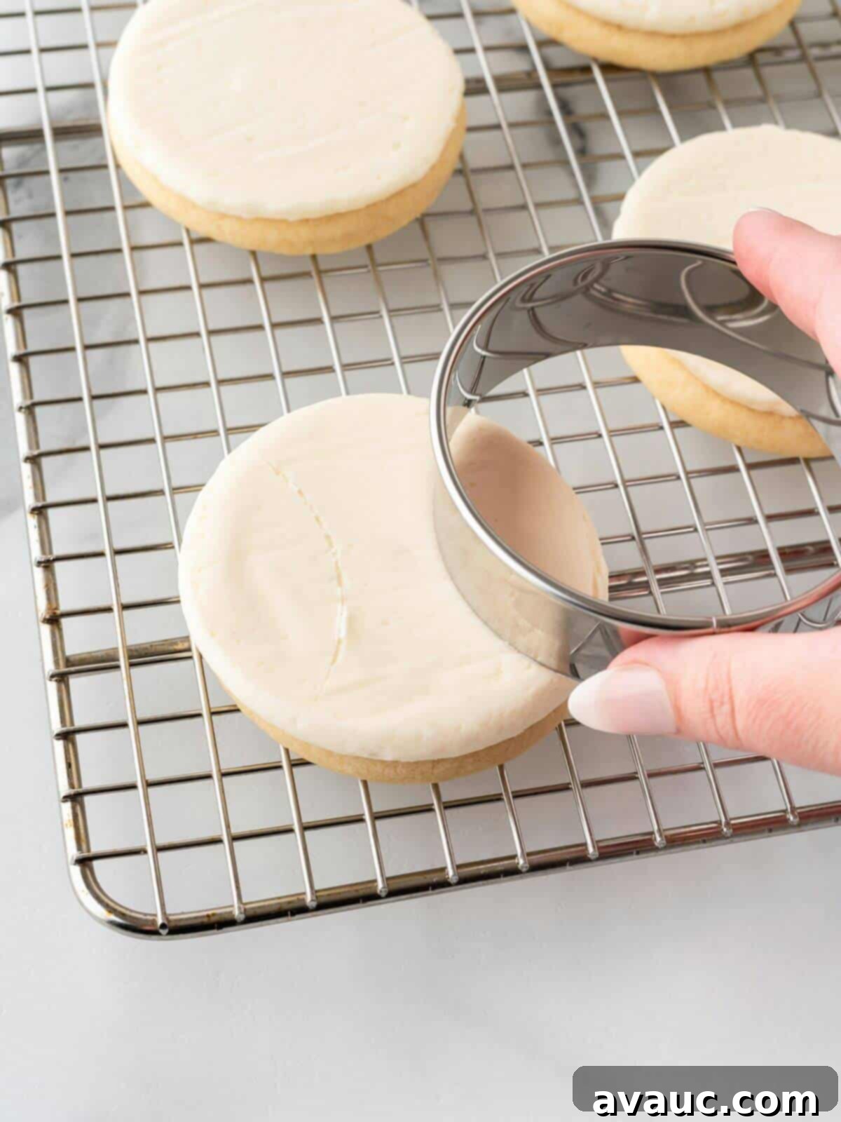 Using a round cookie cutter to gently indent guide lines for baseball seams on a frosted sugar cookie