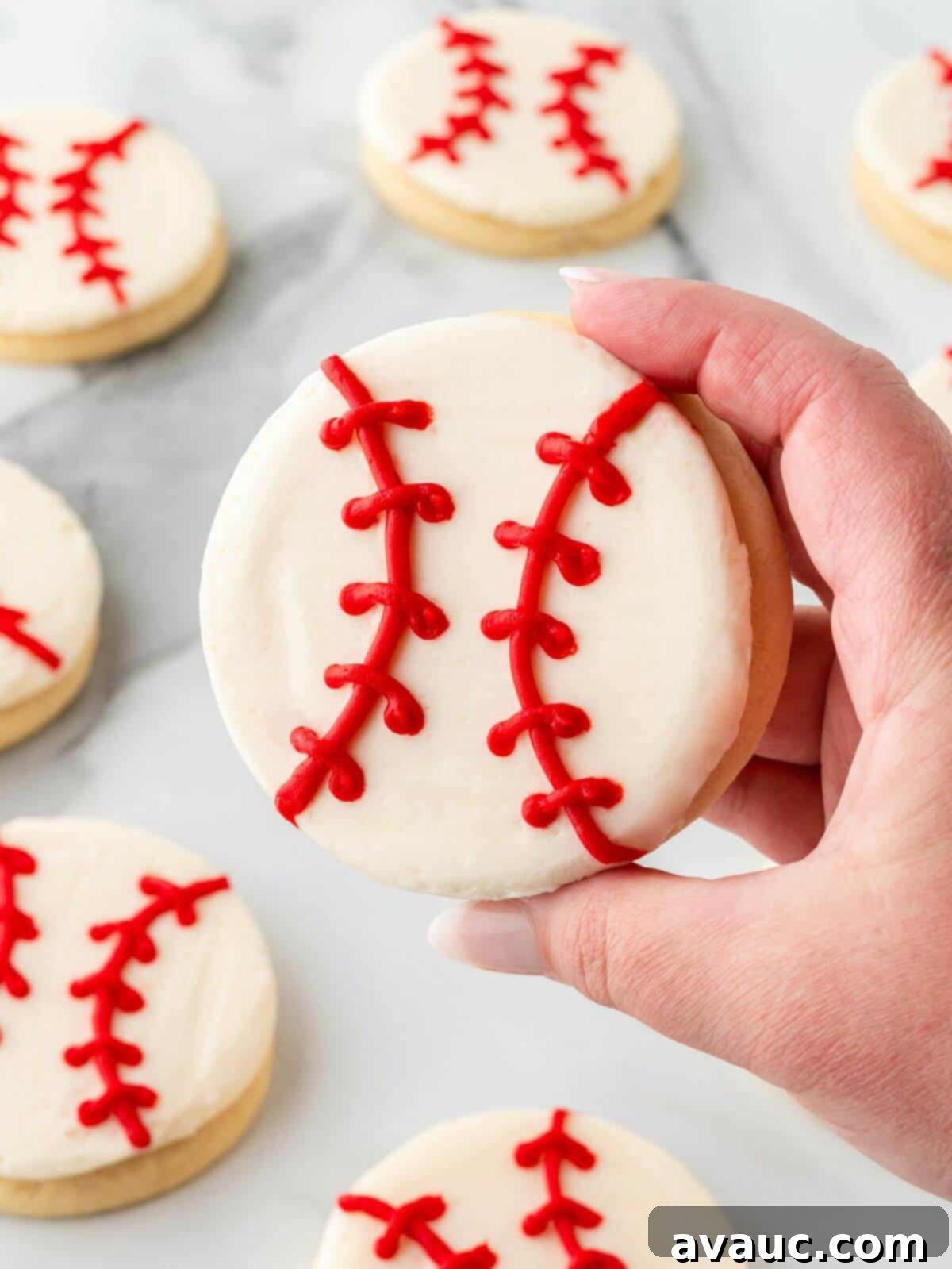 Close-up shot of a perfectly decorated baseball sugar cookie showcasing its red stitches on a white background