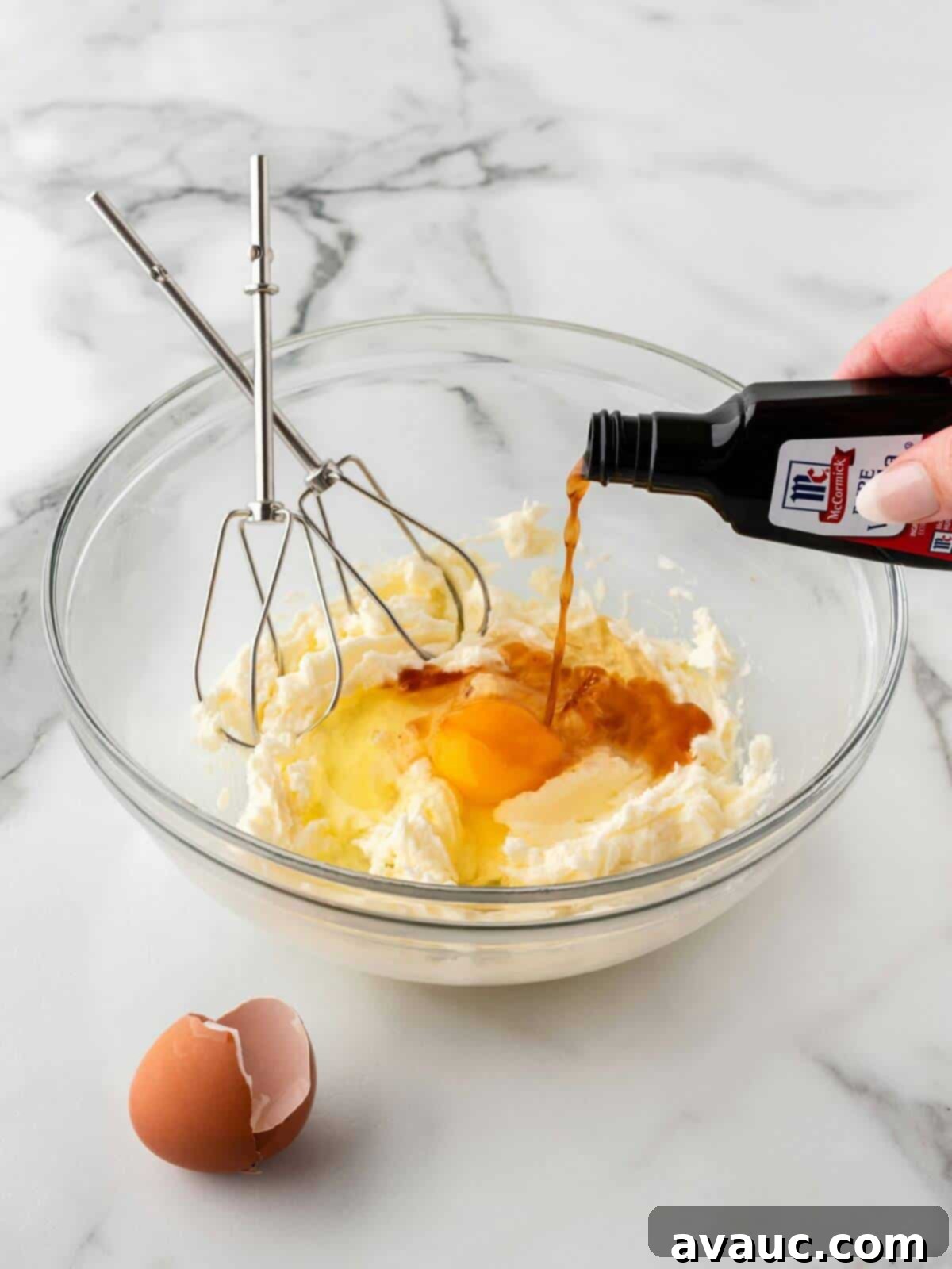 Wet ingredients for sugar cookie dough, including egg and extracts, blended in a glass mixing bowl