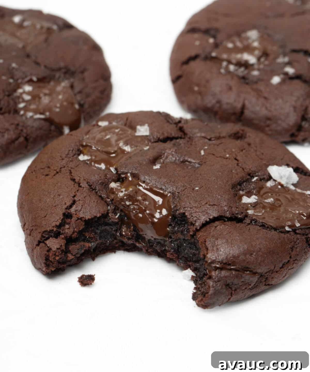 Upclose on a dark chocolate chunk cookie with a bite taken out, showing its fudgy interior.