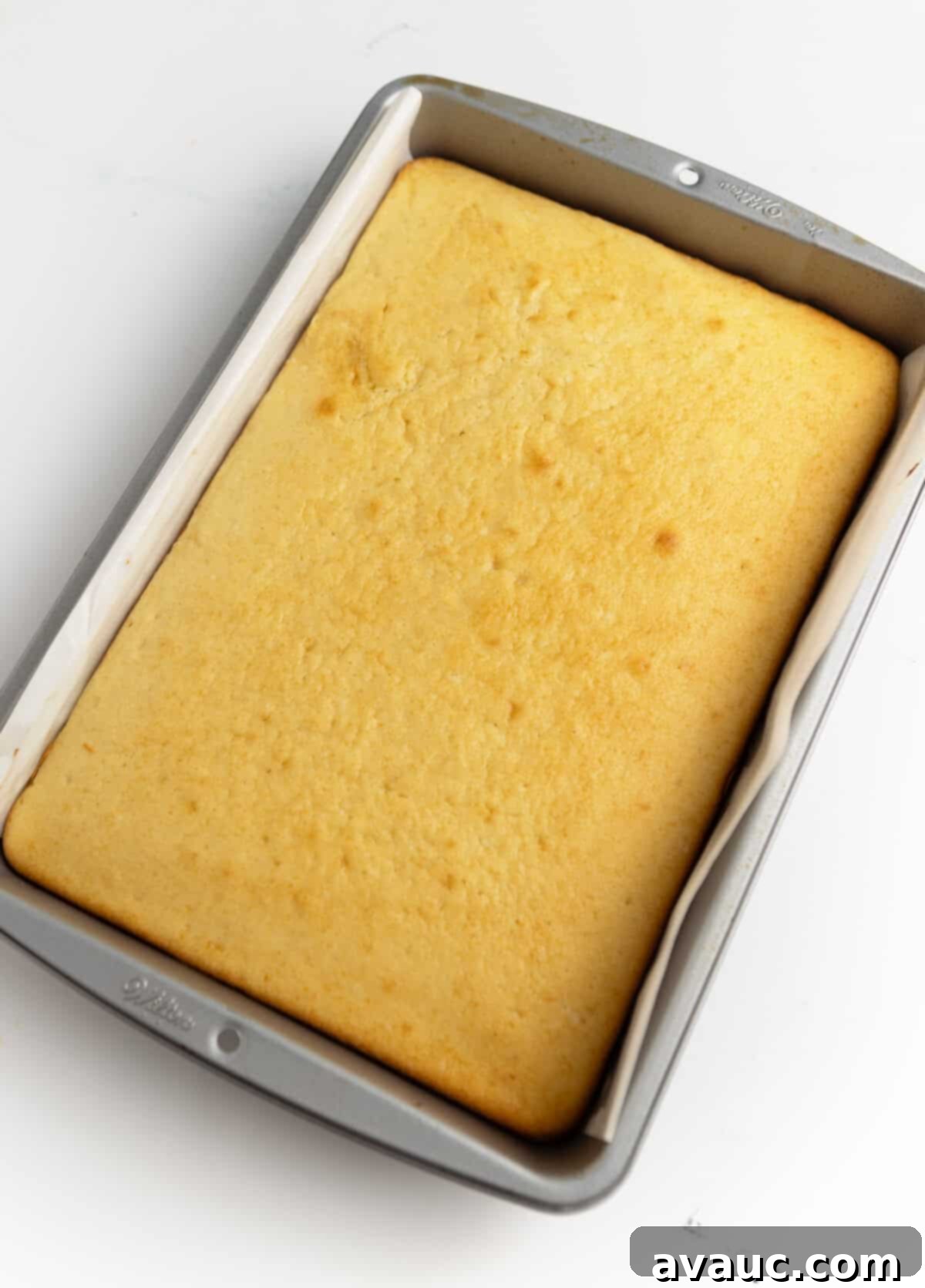 Cake batter spread evenly in a parchment-lined 9x13 inch baking pan, ready for the oven
