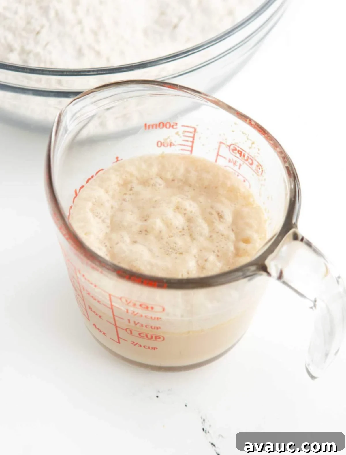Pretzel Hot Dogs in a Flash 5 Glass measuring cup showing bloomed yeast with a layer of foam on top.