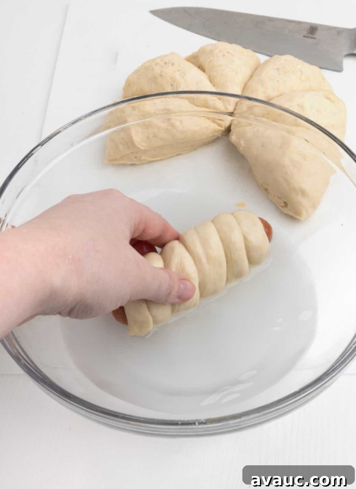 Pretzel Hot Dogs in a Flash 10 Hand dipping a pretzel hot dog in a baking soda water bath.