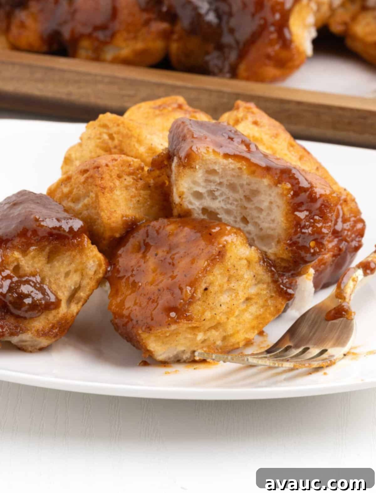 Monkey Bread in a 9x13 Pan 12 A close-up of pull-apart butterscotch monkey bread in a 9x13 pan, with a piece being pulled out, showcasing its soft, gooey texture and glistening glaze.