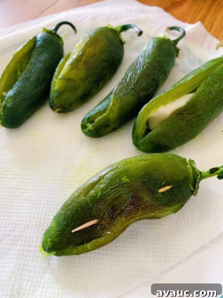 Stuffing jalapeños with a generous piece of white cheese, preparing for a double cheese effect in Chiles Capeados.