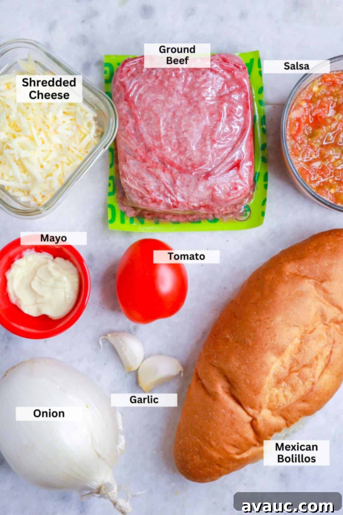 Loaded Cheesy Ground Beef Tortas 3 Ingredients for ground beef tortas: Bowl with shredded cheese, a package of ground beef, a bowl with salsa, a small bowl with mayo, a tomato, a garlic bulb, an onion and a bolillo