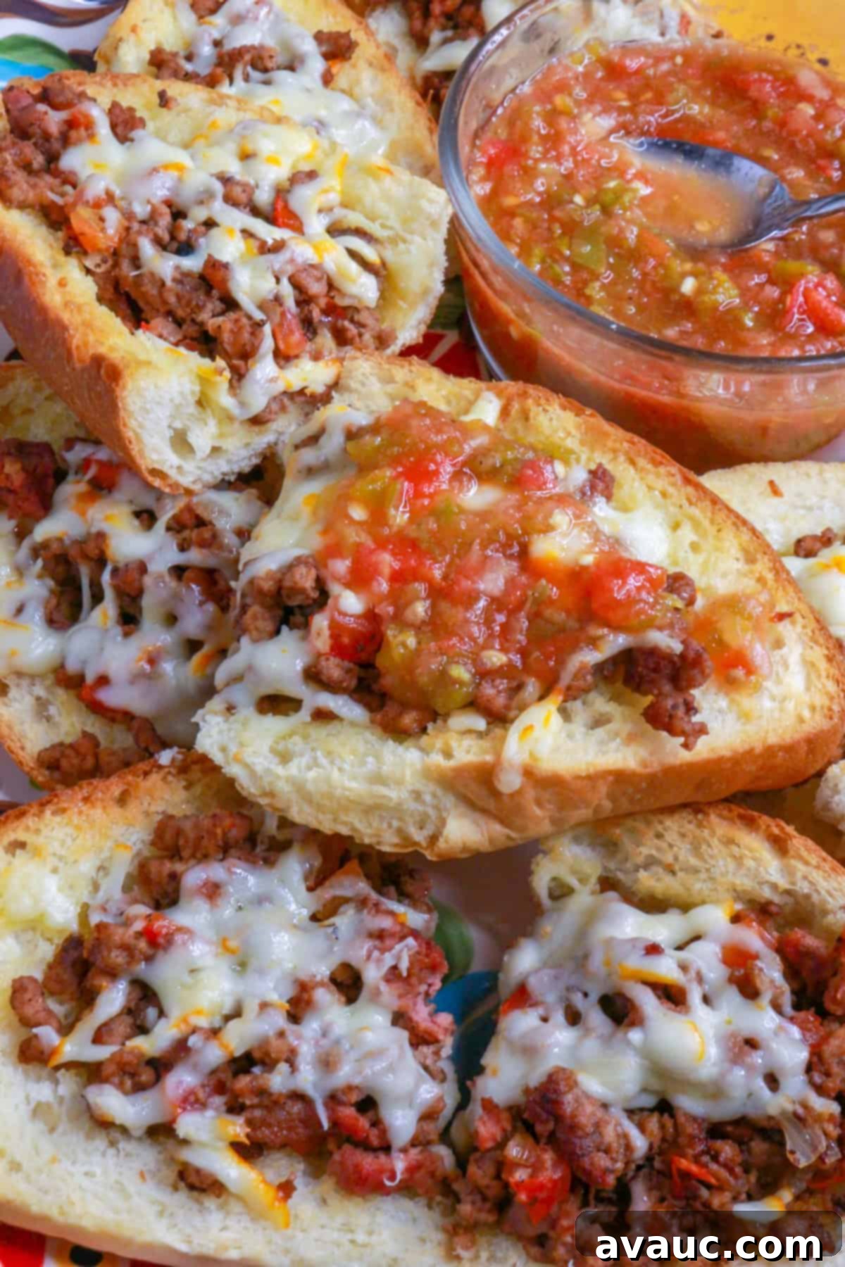 Loaded Cheesy Ground Beef Tortas 8 Close up of open-faced ground beef tortas with a drizzle of jalapeño salsa on a platter