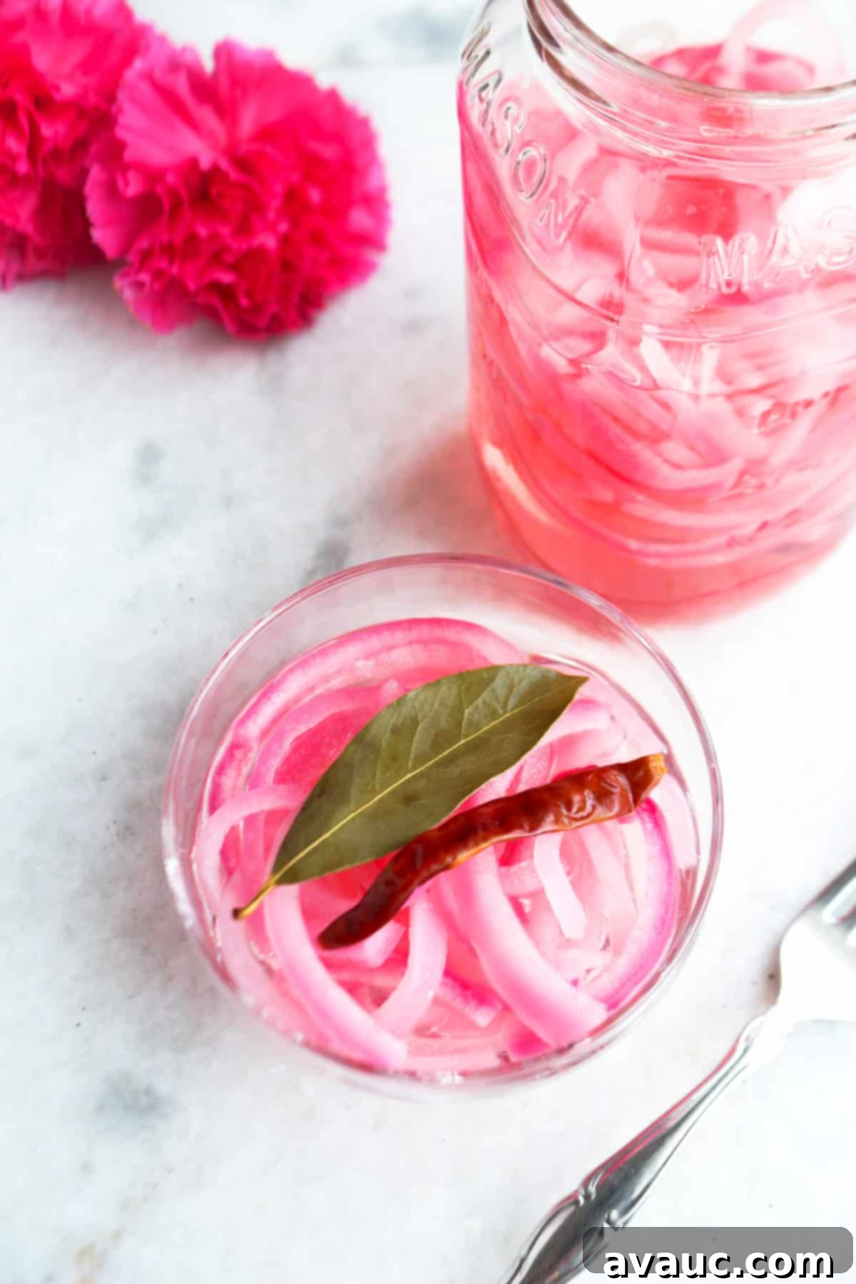 Mexican Pickled Onions 8 Bowl of vibrant Mexican pickled red onions, ready to be served, with a full jar in the background, highlighting the beautiful pink color.
