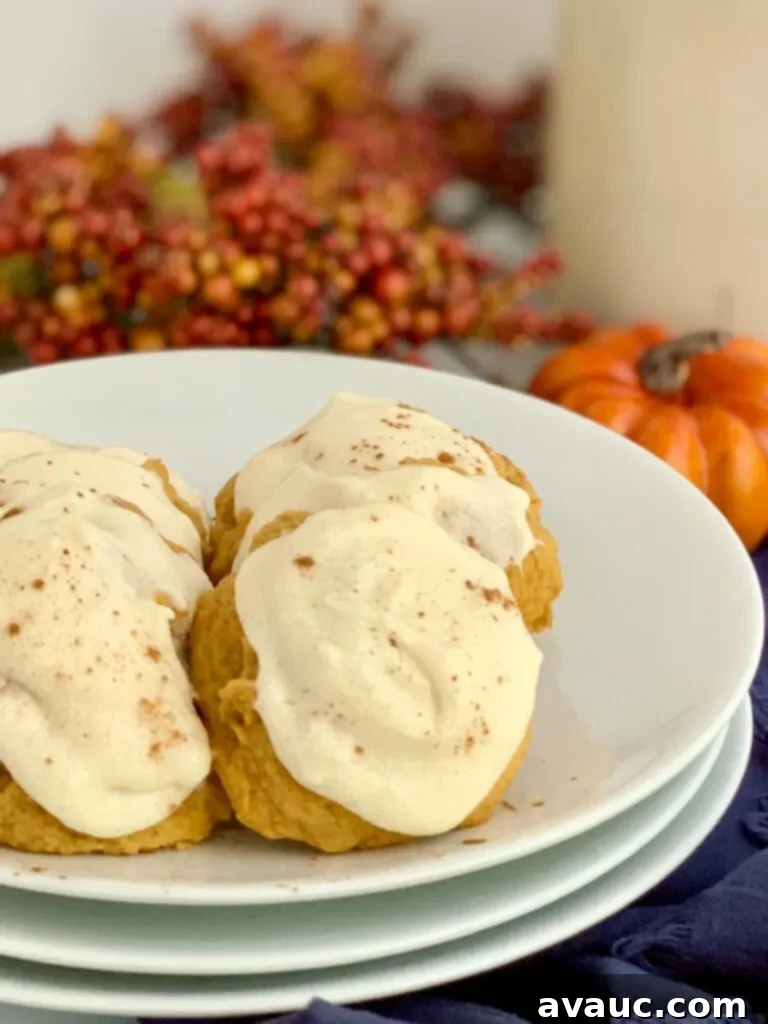 A plate of pumpkin cookies with cream cheese frosting and a dusting of cinnamon