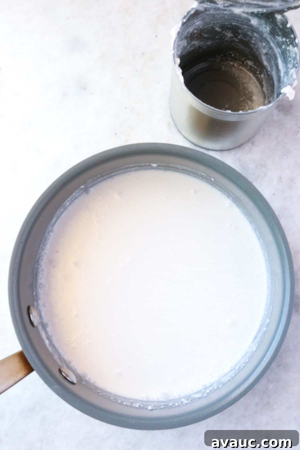 Homemade Coconut Condensed Milk 4 Empty can behind a small pot full of coconut milk