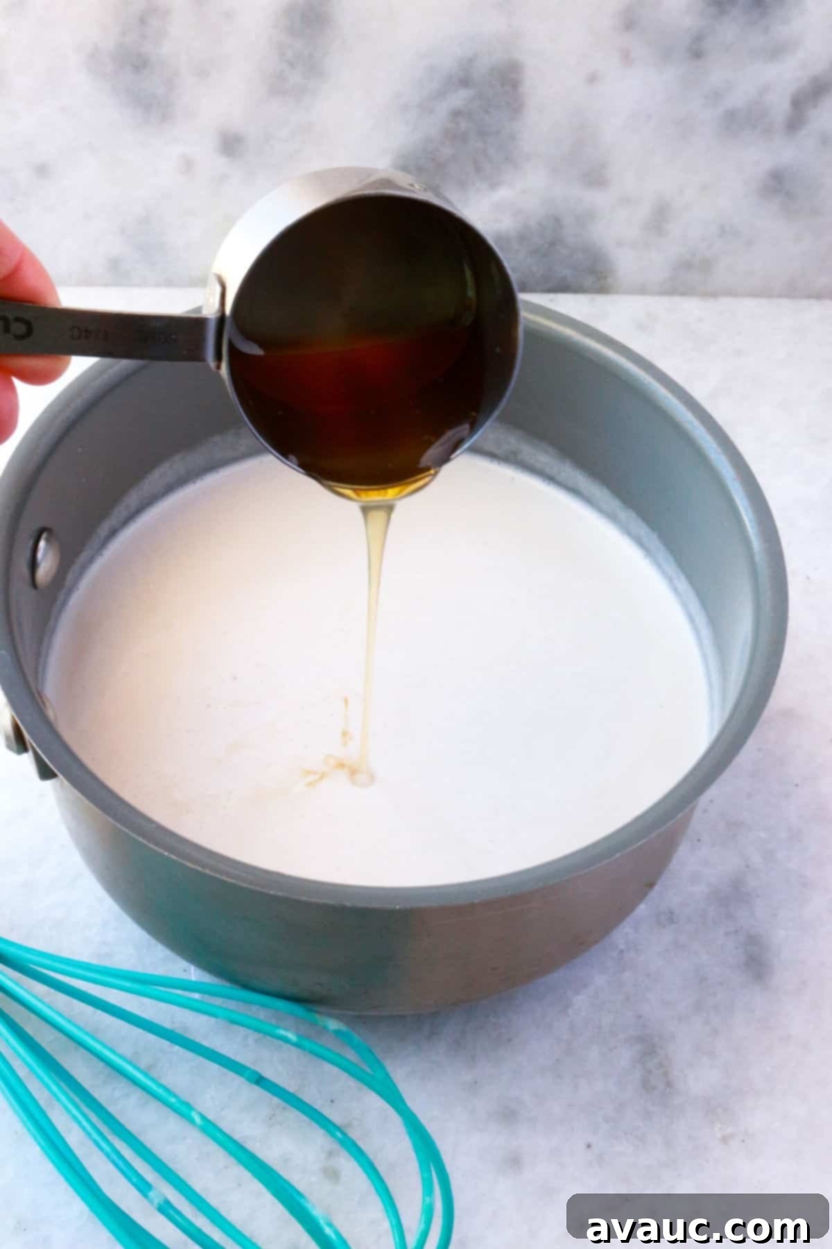 Homemade Coconut Condensed Milk 5 Pouring honey into a pot with coconut milk