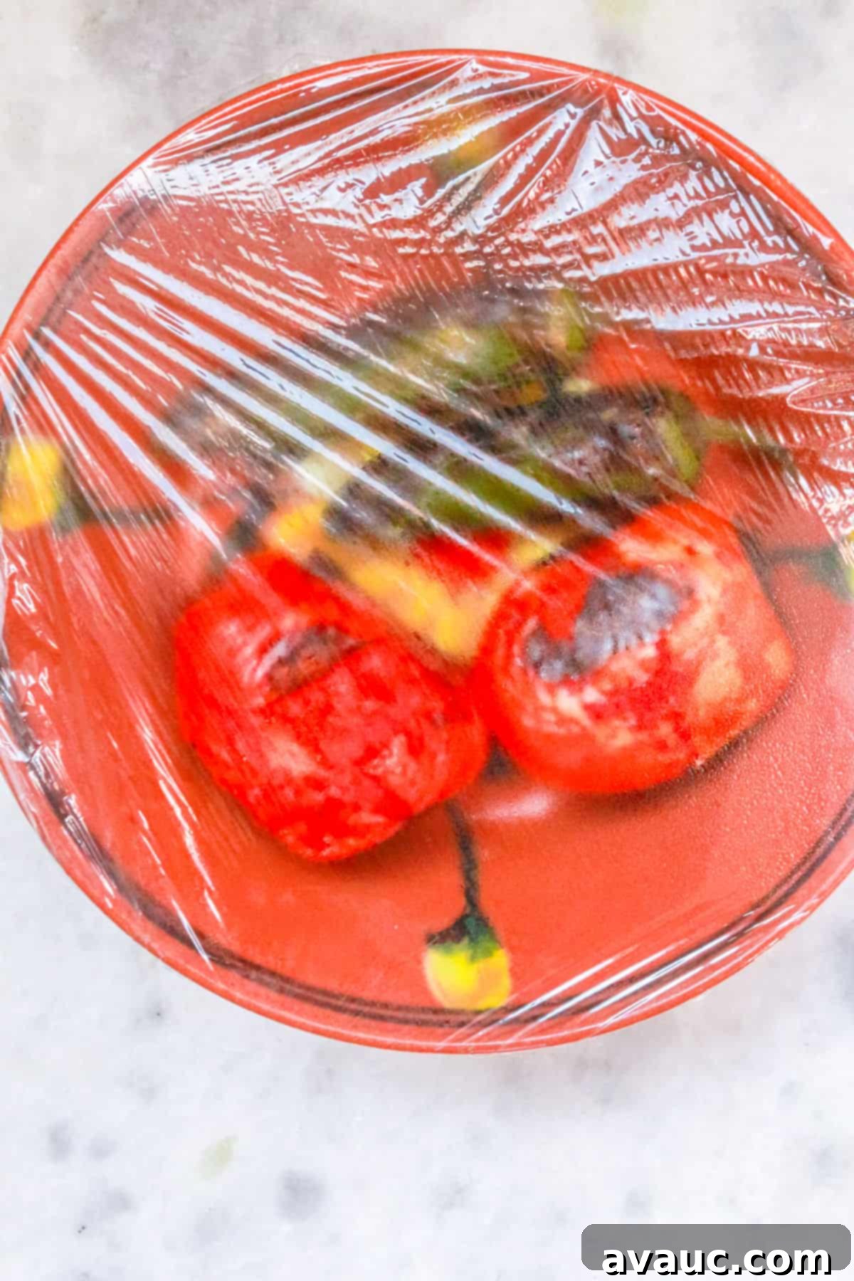 Smoky Simplicity Guacamole with Only Four Ingredients 5 Roasted jalapeños and tomatoes in a bowl covered with plastic-wrap