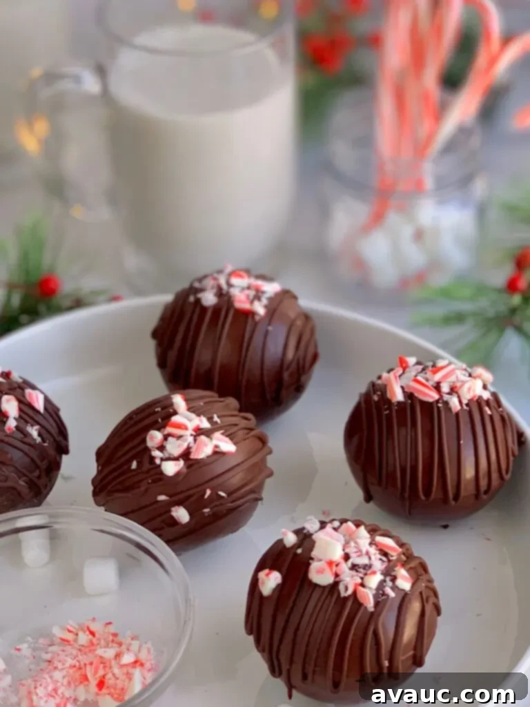 Five hollow chocolate spheres, generously filled with hot cocoa mix and mini marshmallows, elegantly topped with a drizzle of melted chocolate and crushed candy canes.