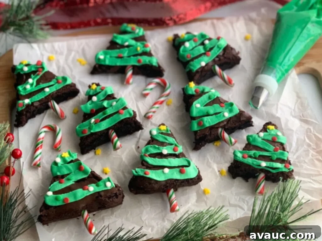 Rich chocolate brownies cut into charming Christmas tree shapes, adorned with zig-zag green frosting and colorful festive sprinkles.