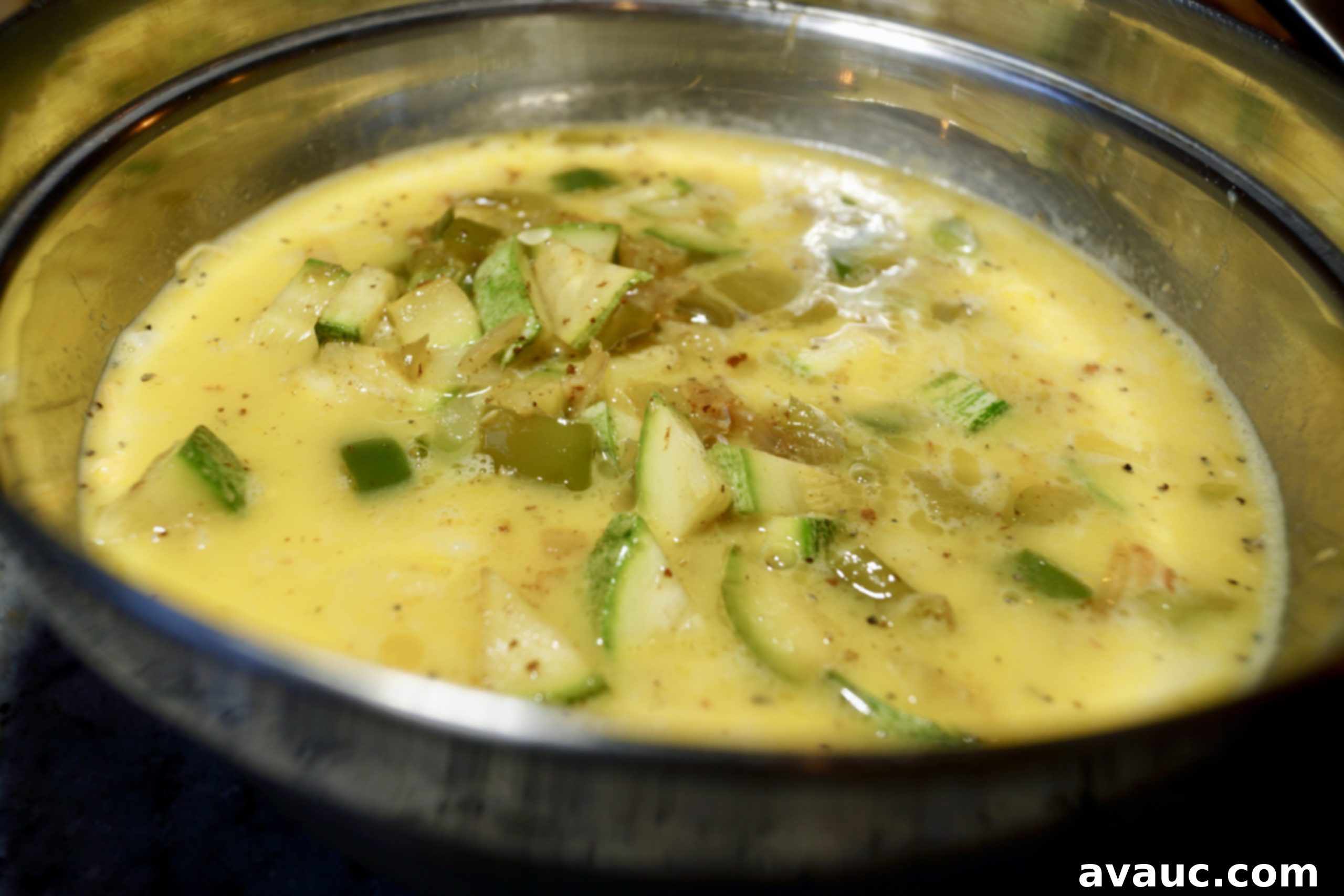 Egg mixture with hash browns, cheese, and vegetables ready for baking