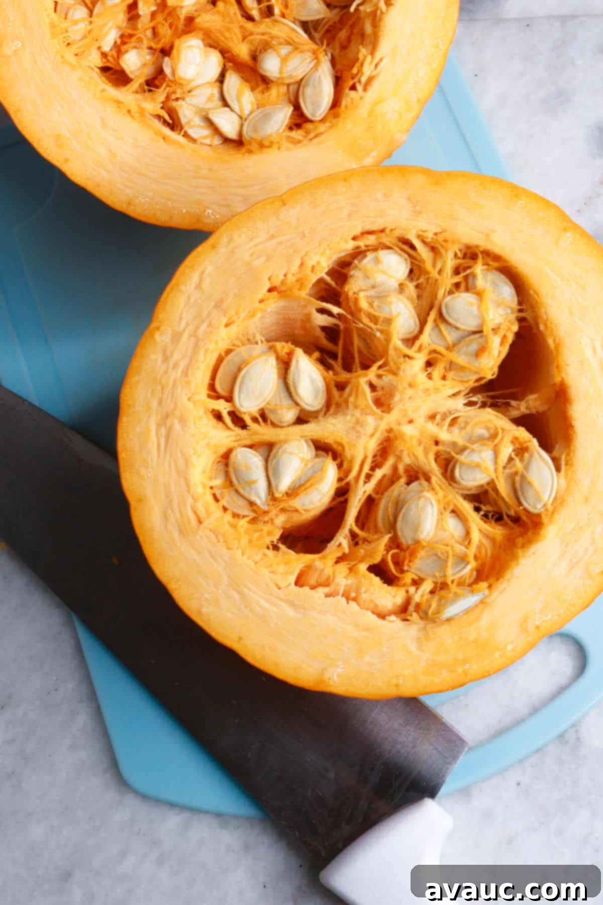 Pumpkin Empanada Filling 4 A whole pumpkin cut neatly in half, revealing its seeds and fibrous interior.