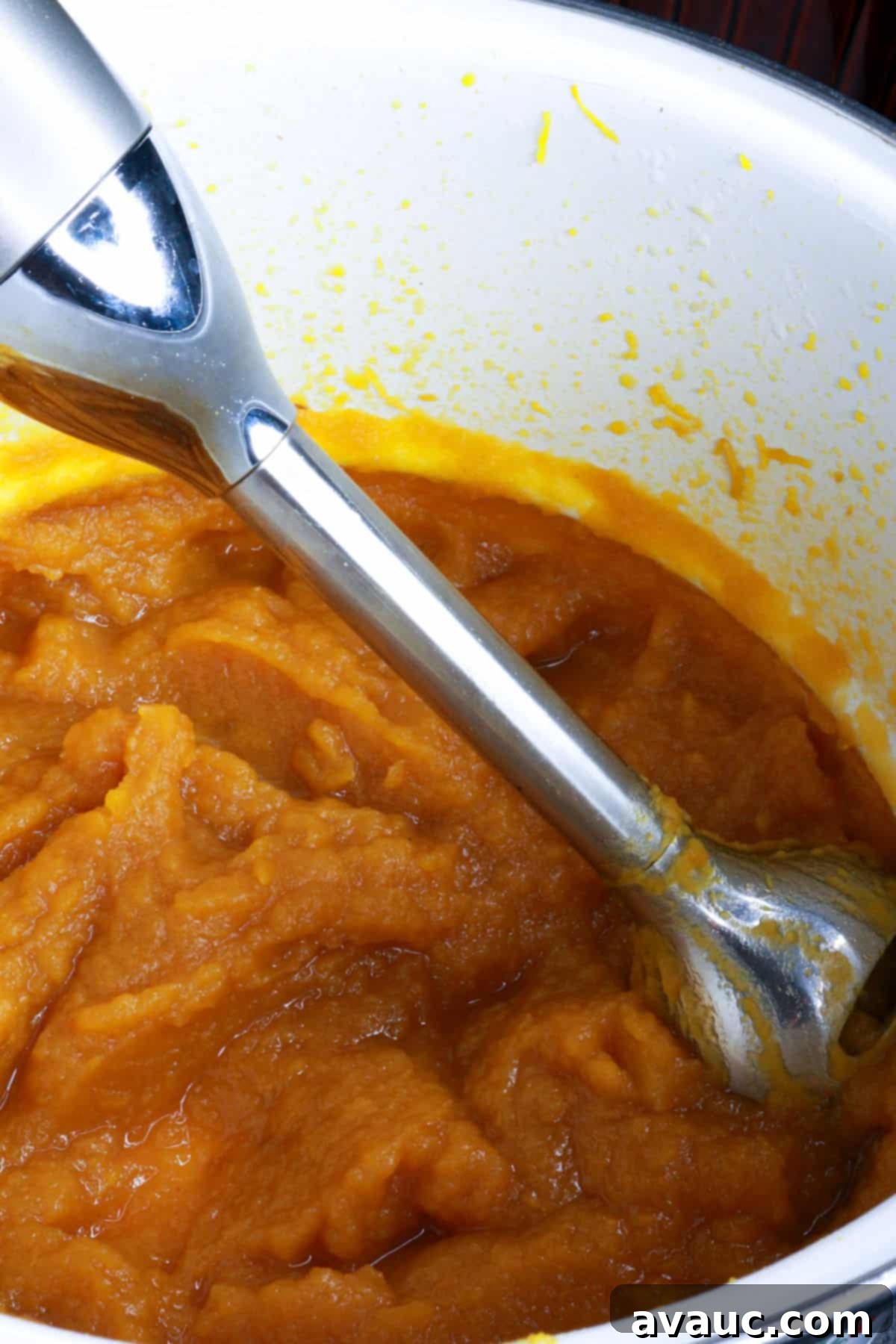 Pumpkin Empanada Filling 9 An immersion blender actively pureeing cooked pumpkin directly in the pot, creating a smooth mixture.