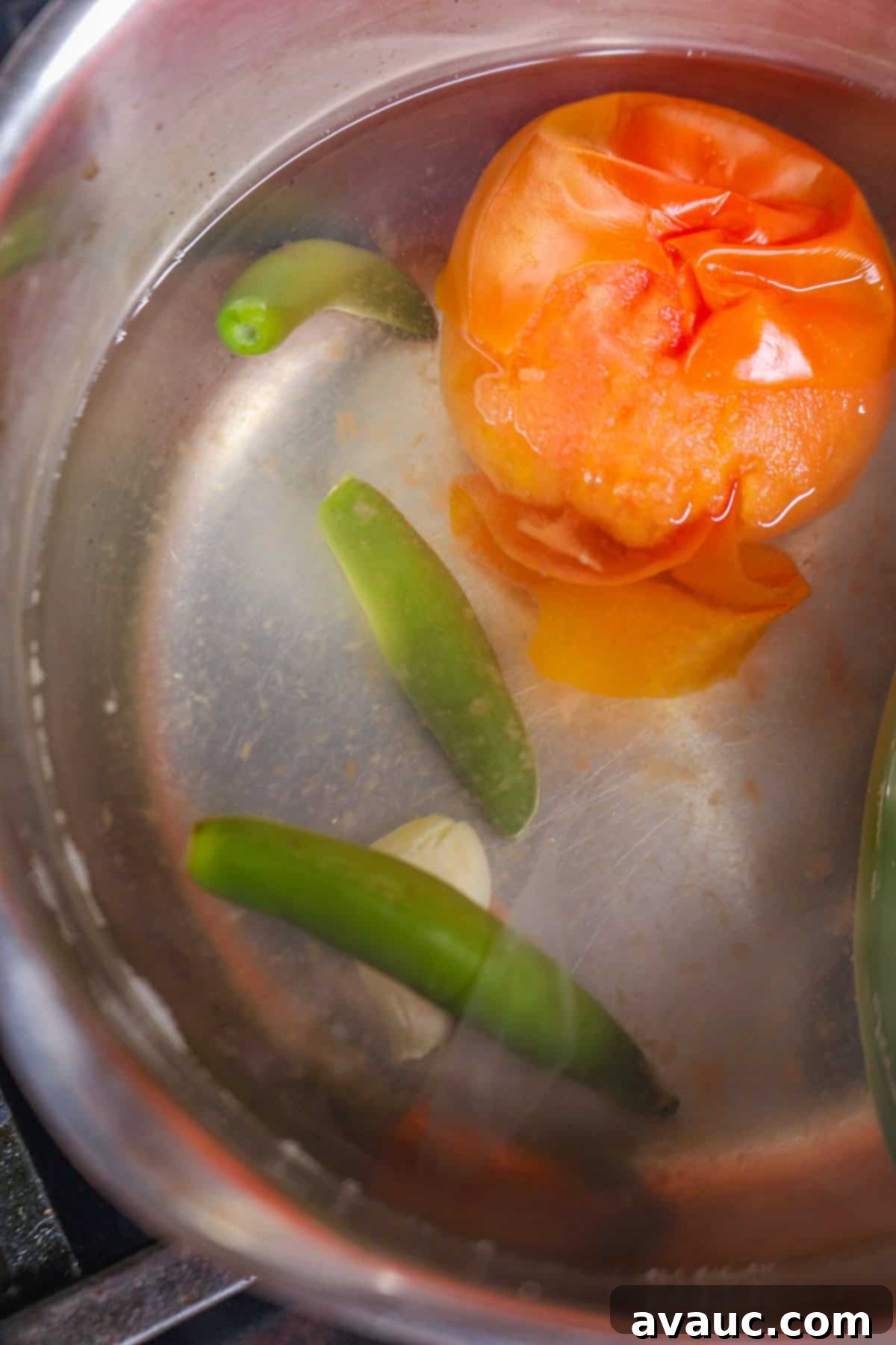 Boiling a tomato, garlic, and serranos in a pot for Serrano pepper salsa