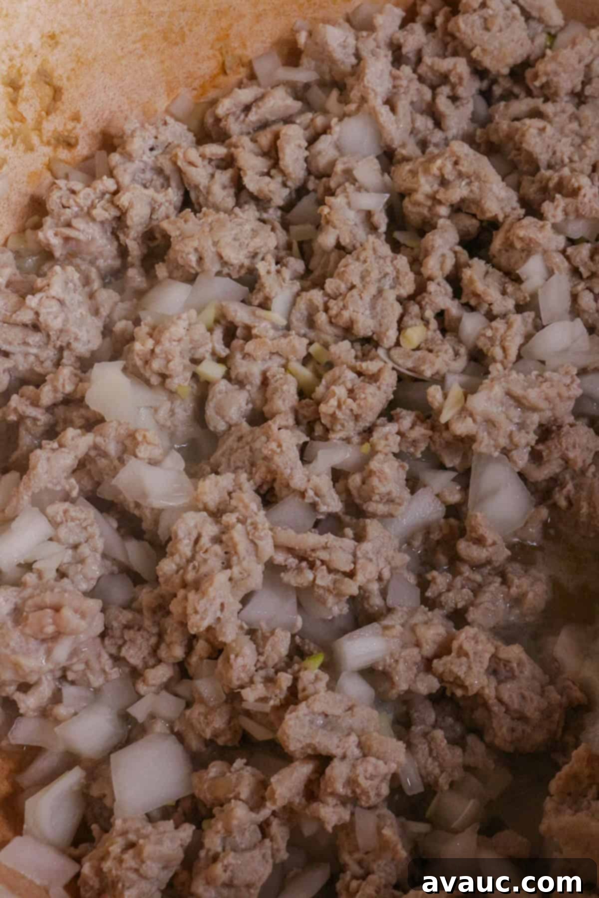 Ground turkey with diced garlic and onion cooking in a pot