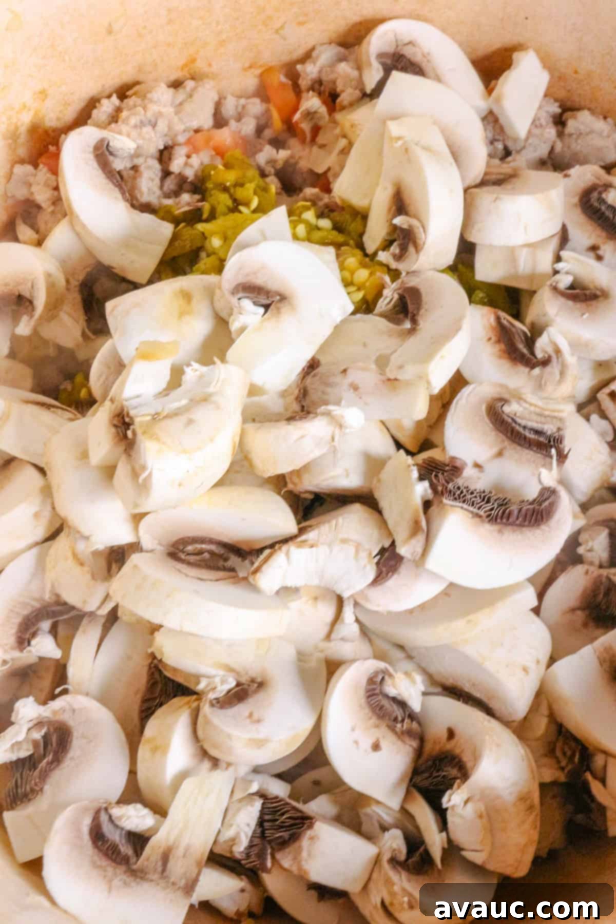 Sliced mushrooms in the pot with turkey and chiles