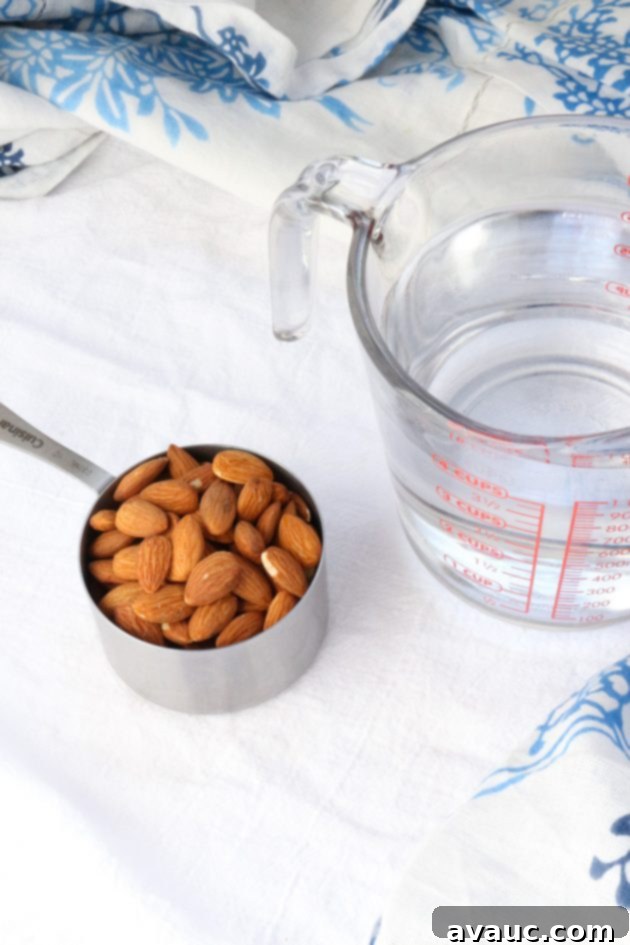 Cup of almonds and measuring cup with water for Healthy Homemade Almond Milk (Paleo & Whole30)