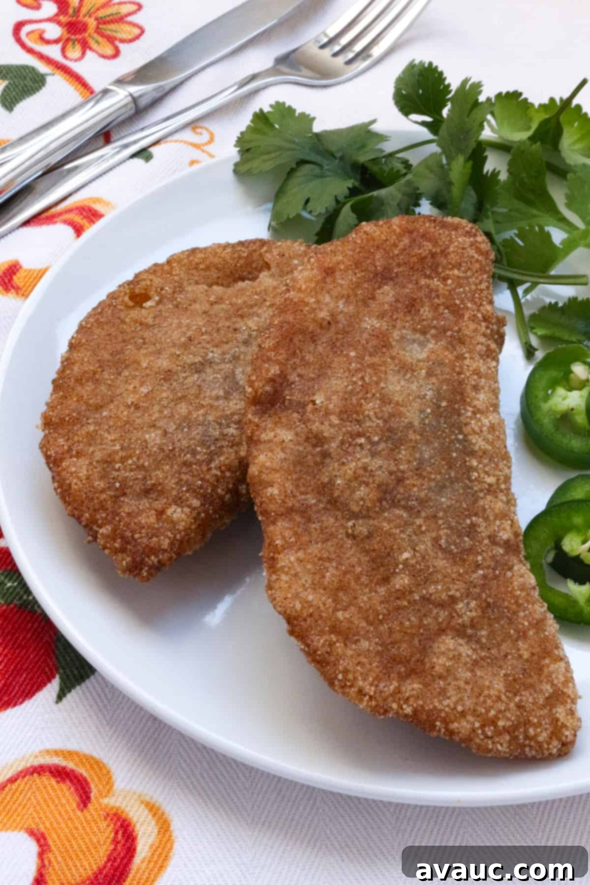 Savory Gluten-Free Sardine Empanadas 2 Two gluten-free empanadas de sardina on a plate with cilantro and jalapeño slices beside them.
