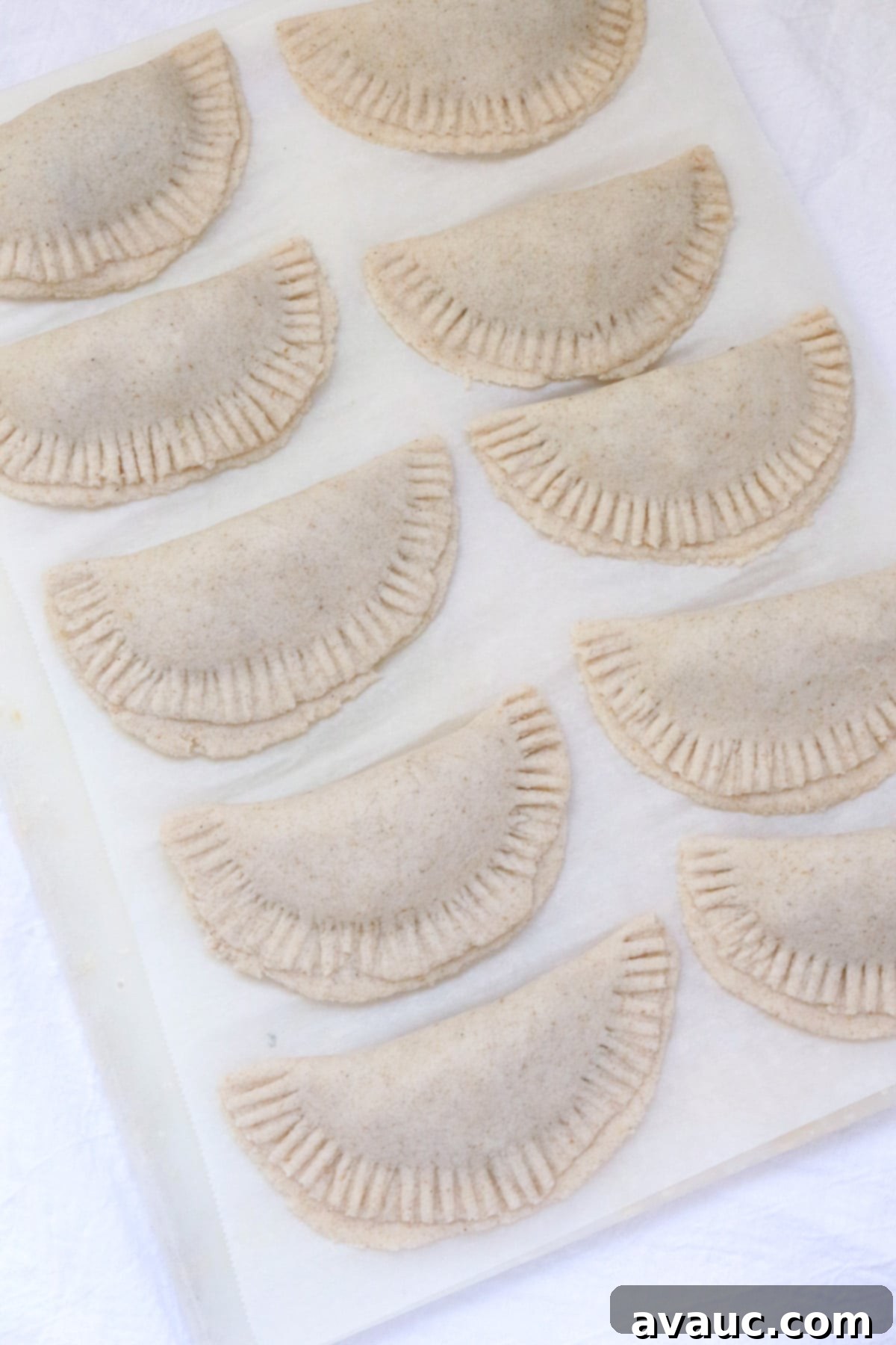 Savory Gluten-Free Sardine Empanadas 9 Gluten-free empanadas ready to be fried, sitting on a piece of parchment paper