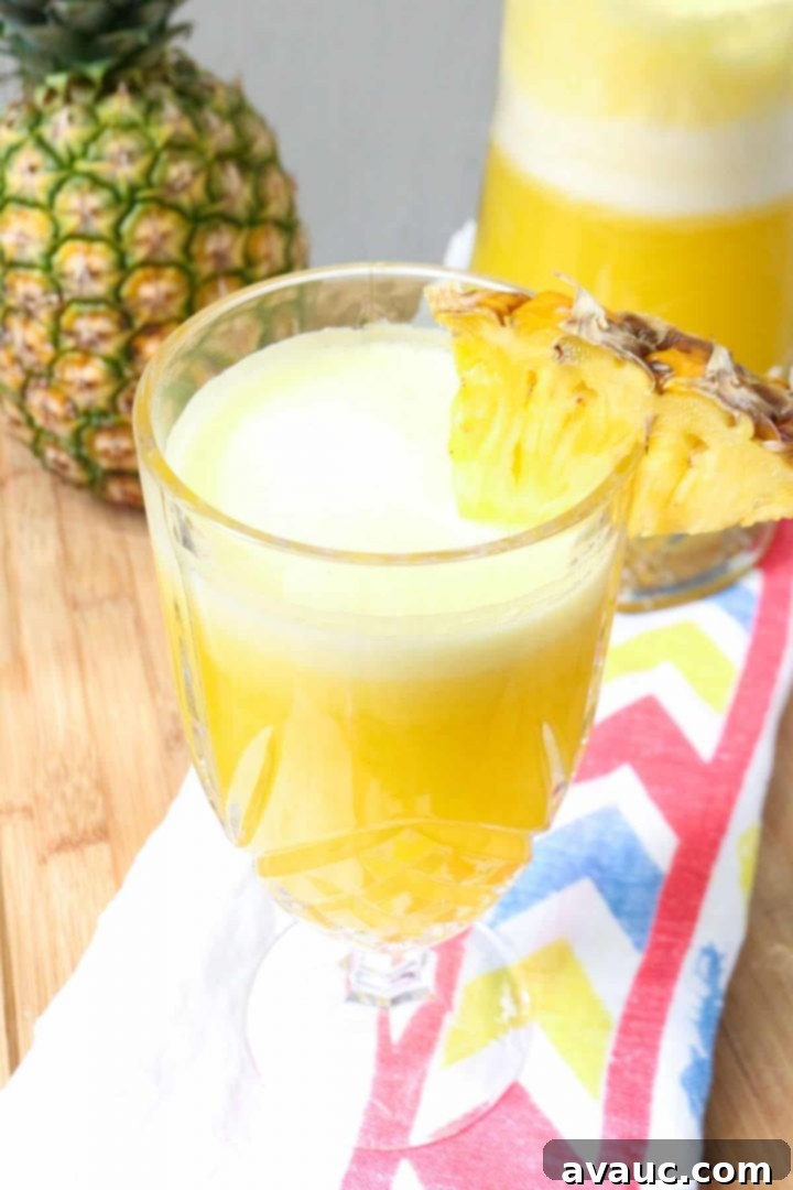 Fresh Pineapple Cooler 8 A tall glass of pineapple agua fresca garnished with fresh mint and pineapple wedges.