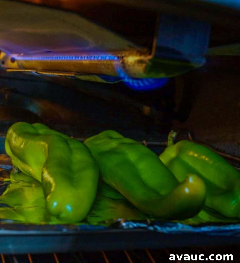 Smoky Roasted Green Chile Guacamole 4 Green chiles being roasted under a broiler, showing charring on the skin