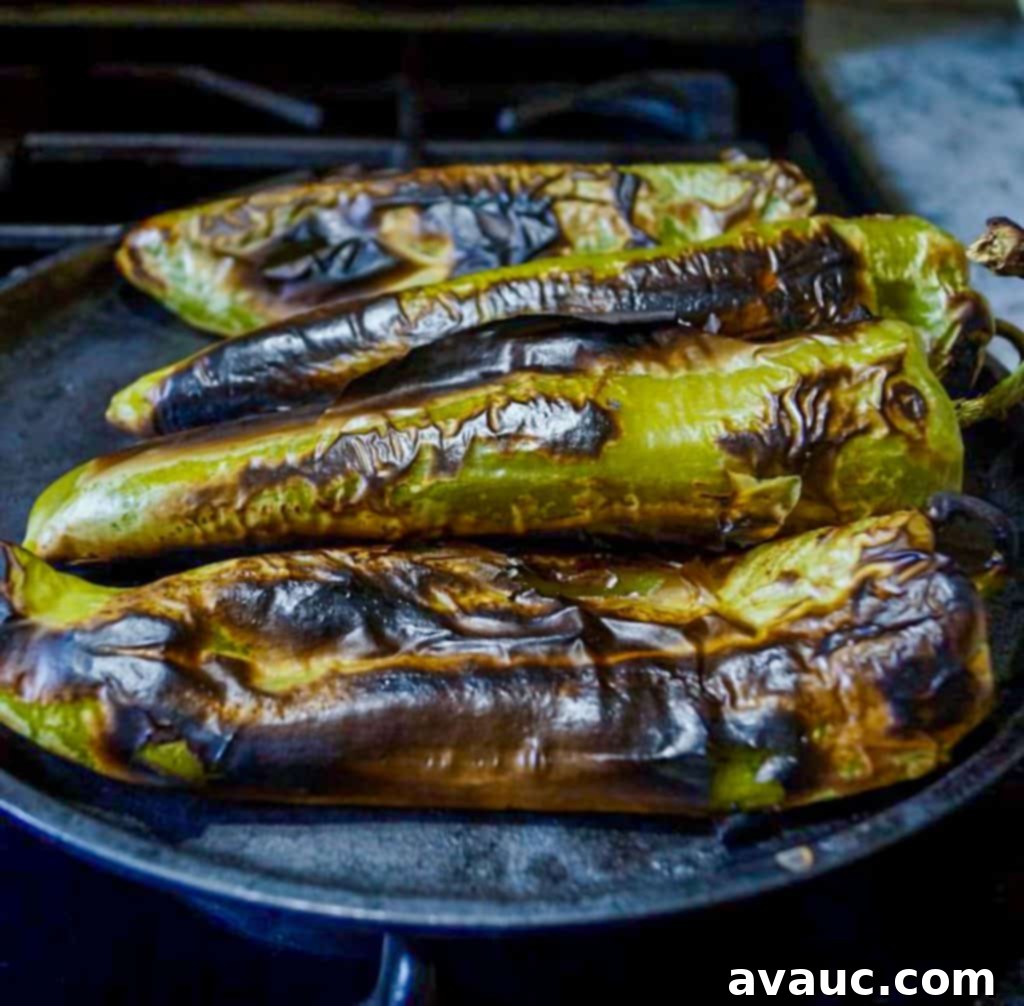 Smoky Roasted Green Chile Guacamole 5 Roasted green chiles cooling on a comal on the stovetop, skins visibly charred
