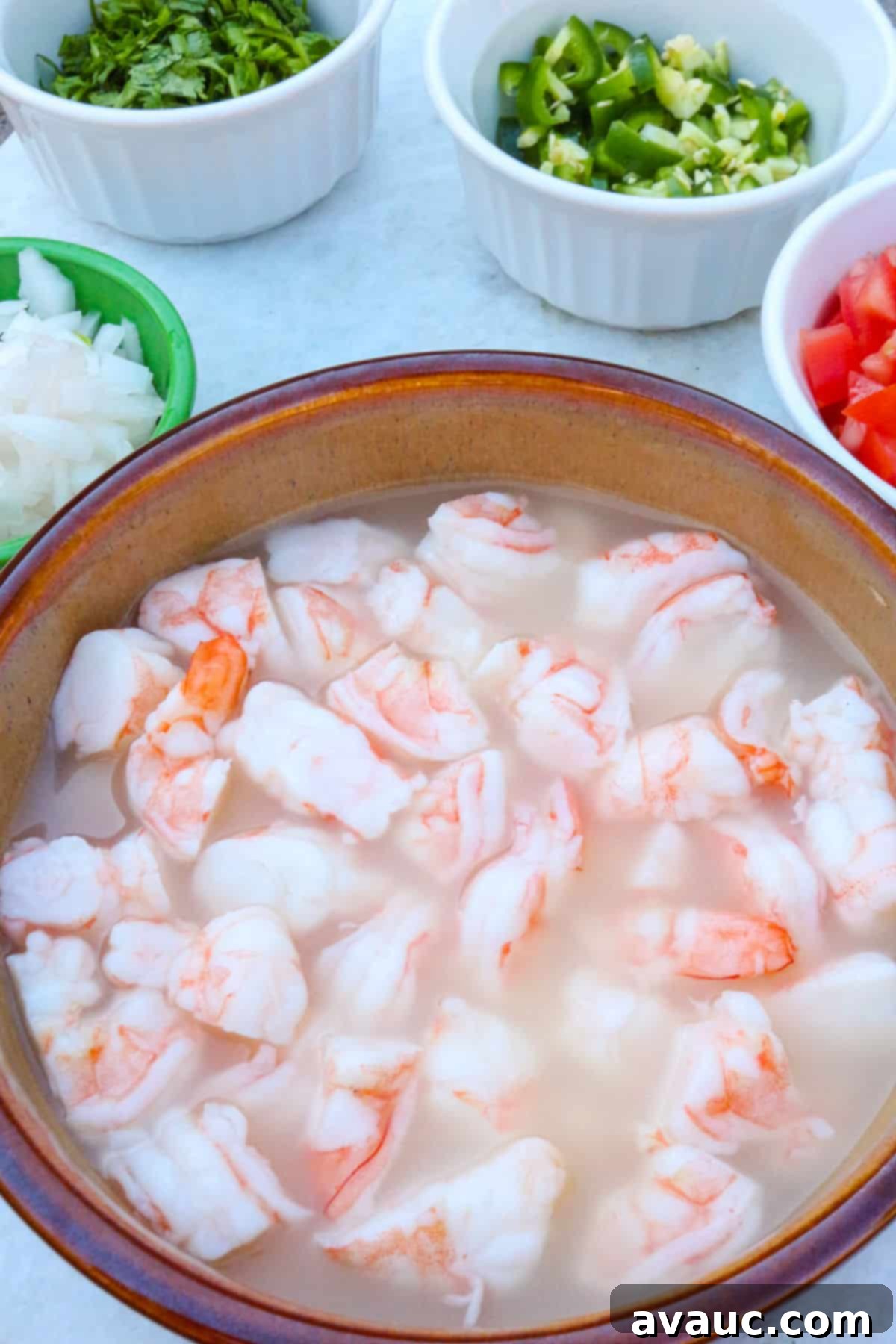 Zesty Mexican Shrimp Ceviche 4 A bowl with shrimp in lime juice with bowls with diced veggies around it