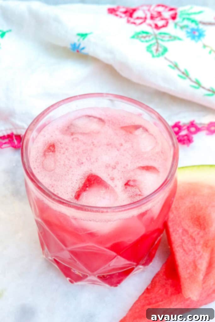 A glass of Agua de Sandia garnished with a watermelon wedge and mint sprig