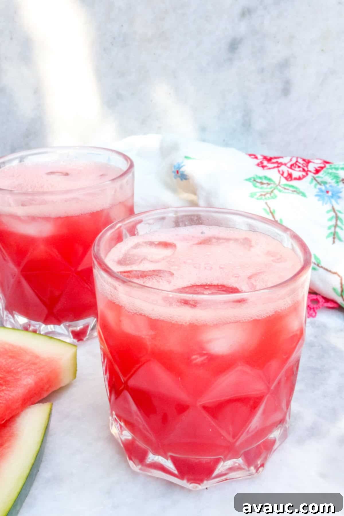 Two glasses of vibrant watermelon agua fresca (agua de sandia) with watermelon wedges and mint