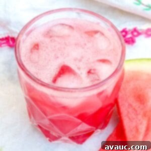 A glass of Agua de Sandia with a watermelon slice and mint sprig