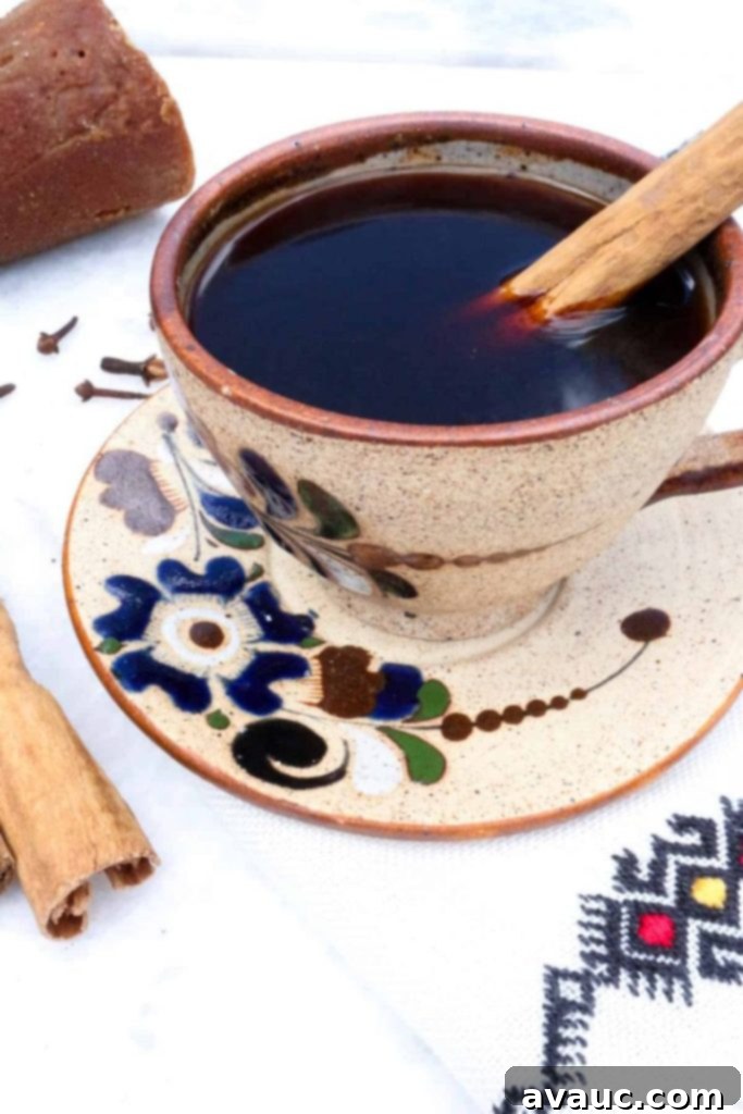 Authentic Café de Olla Recipe 2 Cafe de Olla in a pottery mug with blue flowers and a cinnamon stick