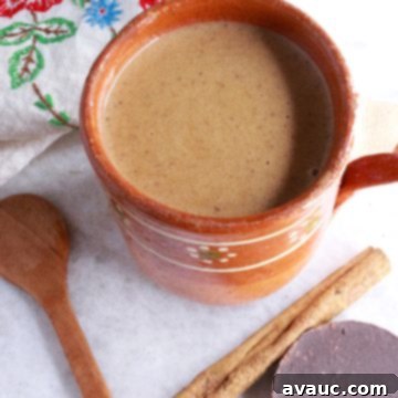Authentic Mexican Champurrado 10 Mug of Mexican Champurrado with wooden spoon, cinnamon stick and Mexican chocolate beside it