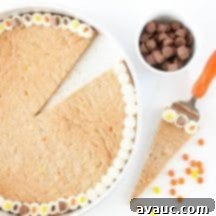 Decadent Reese's Peanut Butter Cookie Cake 5 Close-up of a slice of Reese's Peanut Butter Cookie Cake with frosting and candies.