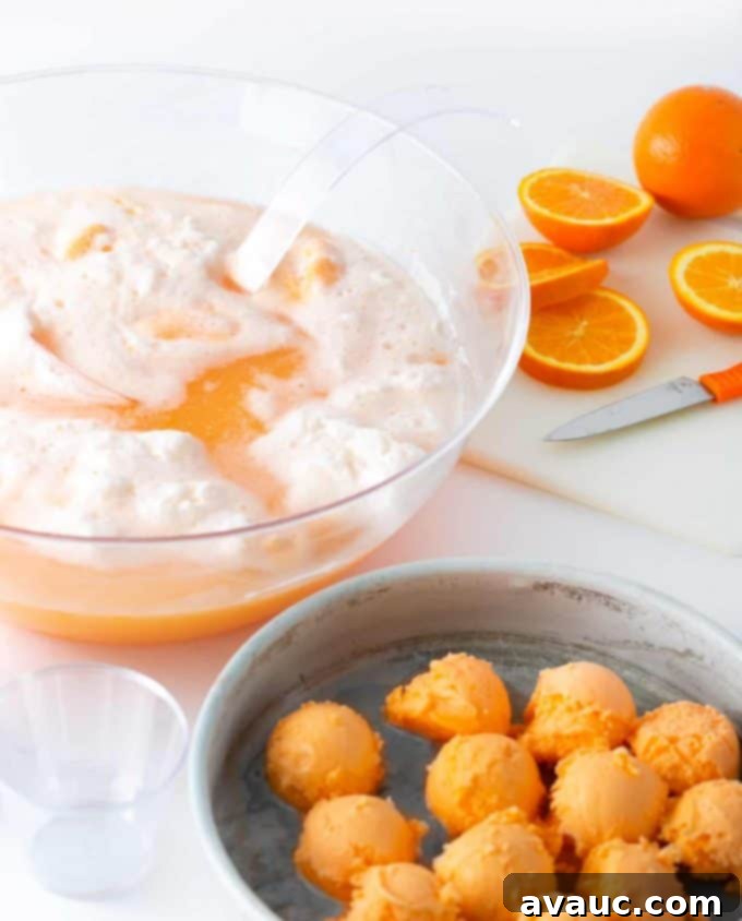 Creamy Orange Fizz 6 Orange Sherbet Punch being stirred in a punch bowl, showing the frothy, bubbly texture as the sherbet melts into the soda and sparkling water.