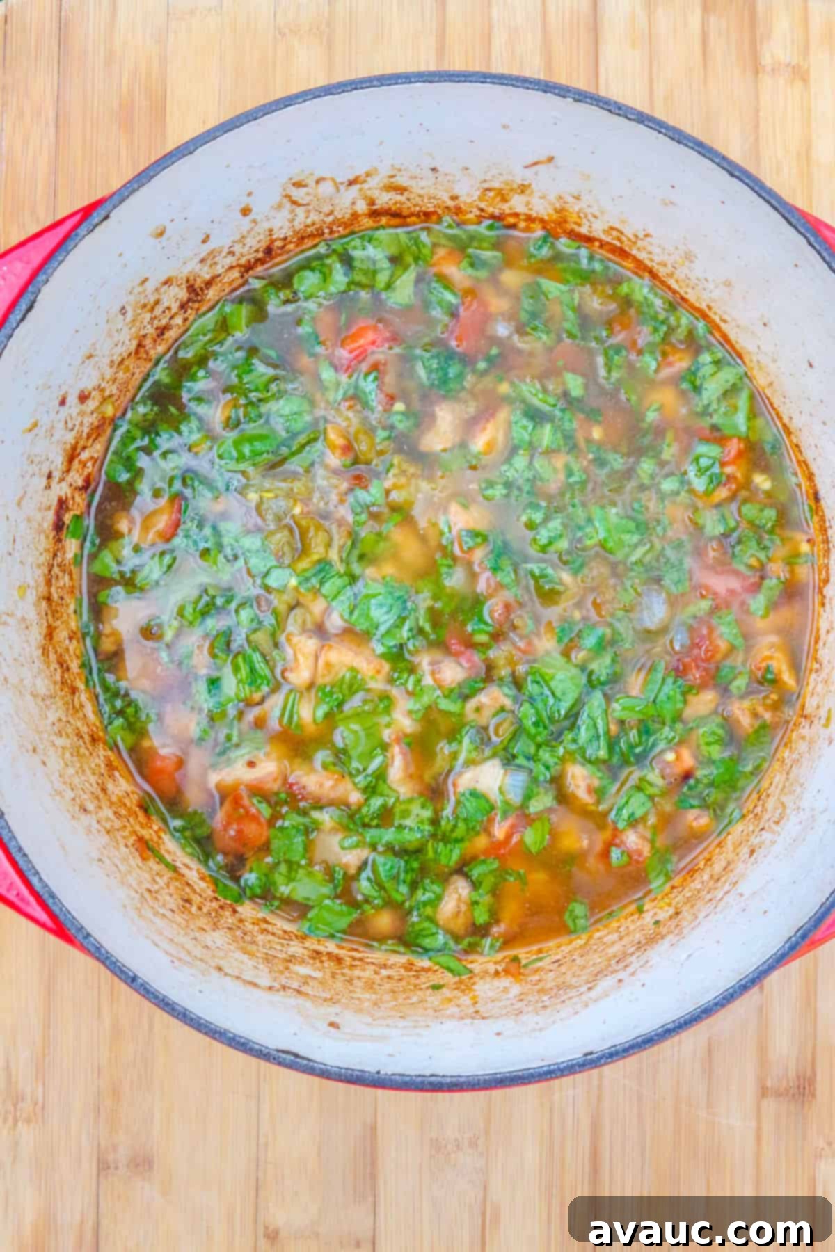 A finished Dutch oven of rich, simmering Colorado Pork Green Chile, showcasing its deep green color and hearty texture, ready to be served.