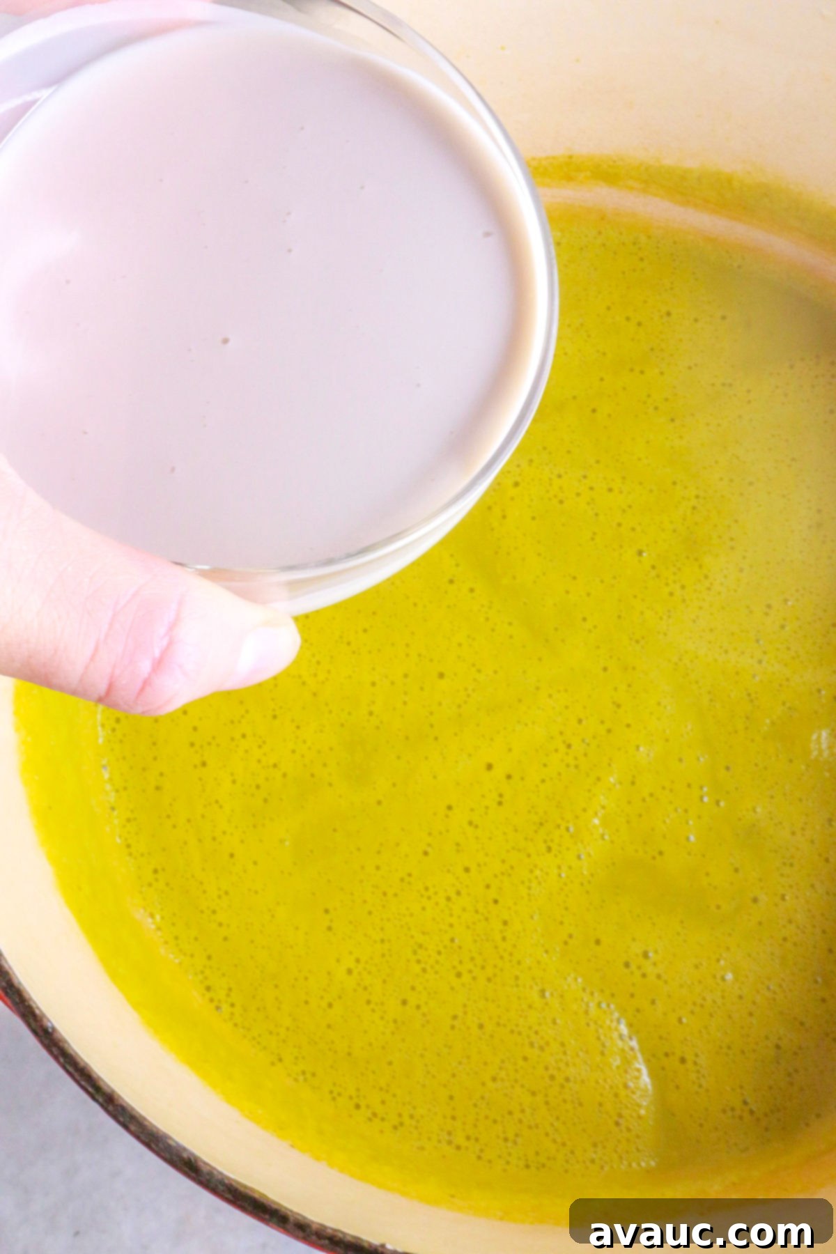 Creamy Dairy-Free Asparagus Soup 9 Adding cream to a pot of asparagus soup
