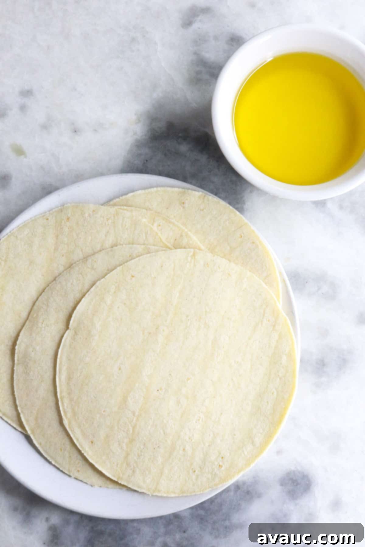 Homemade Tostada Shells Made Easy 3 Fresh corn tortillas stacked next to a small bowl of avocado oil, essential ingredients for homemade tostadas