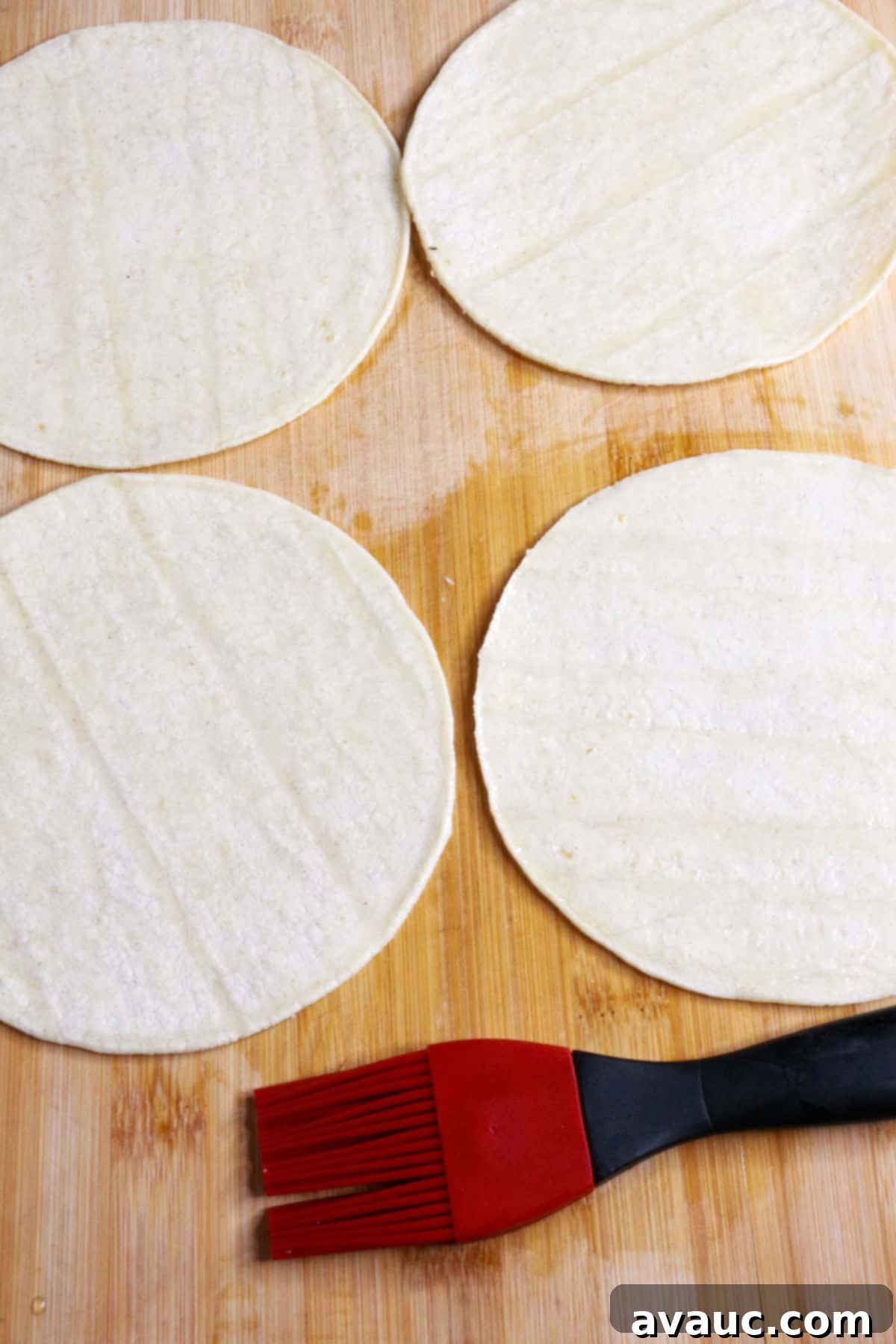 Homemade Tostada Shells Made Easy 7 Four corn tortillas laid out with a pastry brush and small bowl of oil, ready for baking
