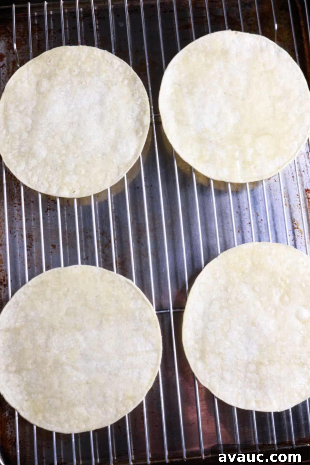 Homemade Tostada Shells Made Easy 8 Four lightly oiled corn tortillas arranged on a wire rack on a baking sheet, ready for the oven