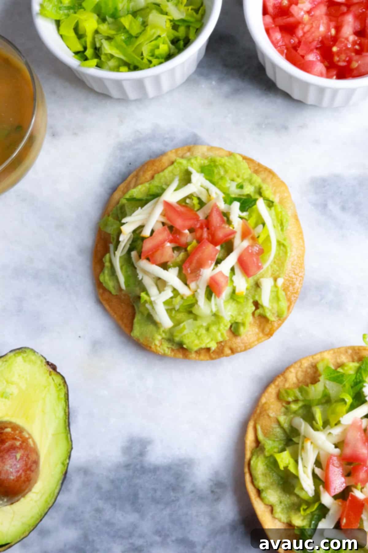 Delicious Avocado Tostadas 2 Avocado tostadas with tomato, lettuce, a container of salsa, and half of an avocado, ready to be enjoyed as a fresh, healthy meal.