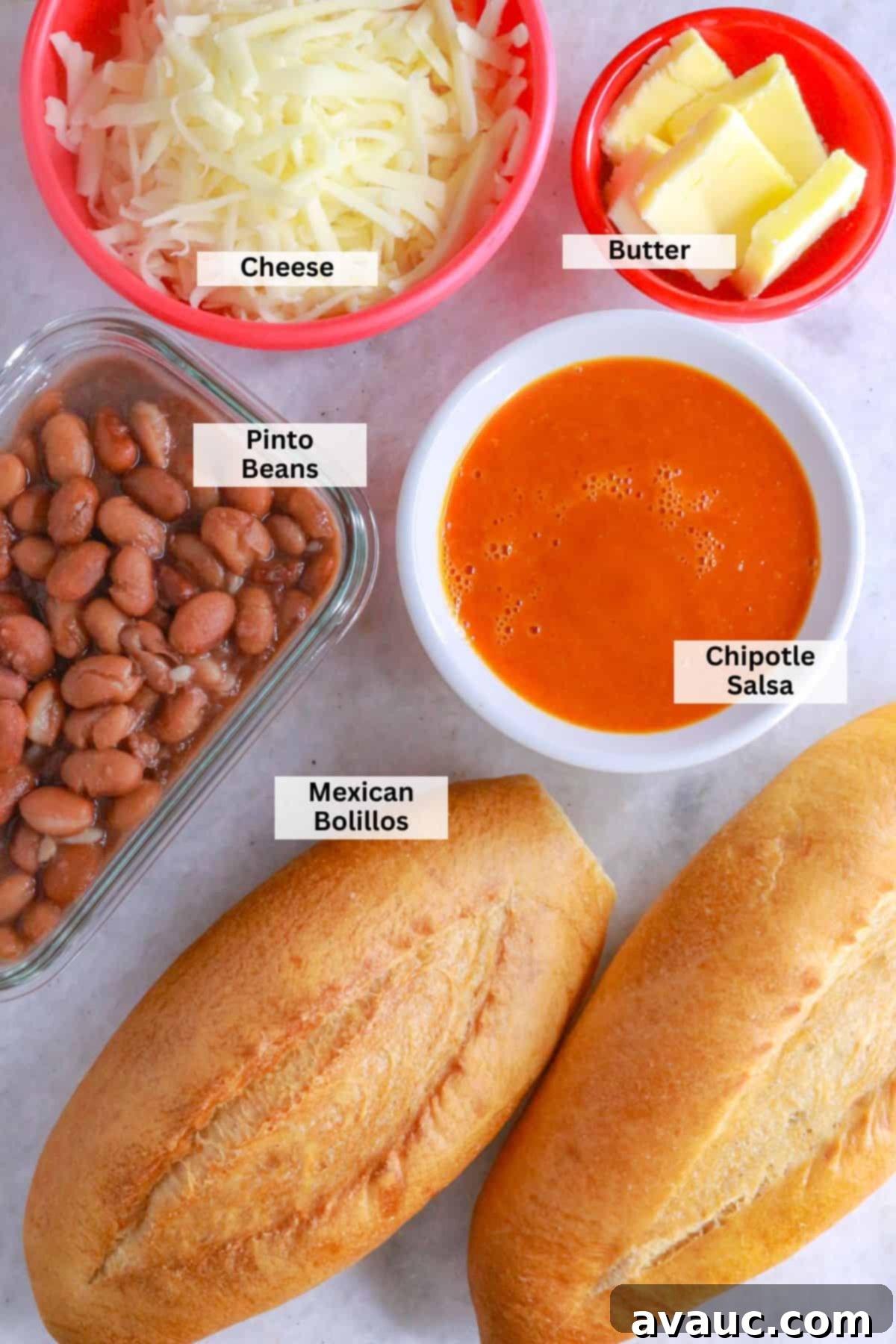 Homemade Mexican Molletes 3 Key ingredients for Mexican molletes: Shredded cheese, butter, pinto beans, chipotle salsa, and bolillos arranged on a wooden board