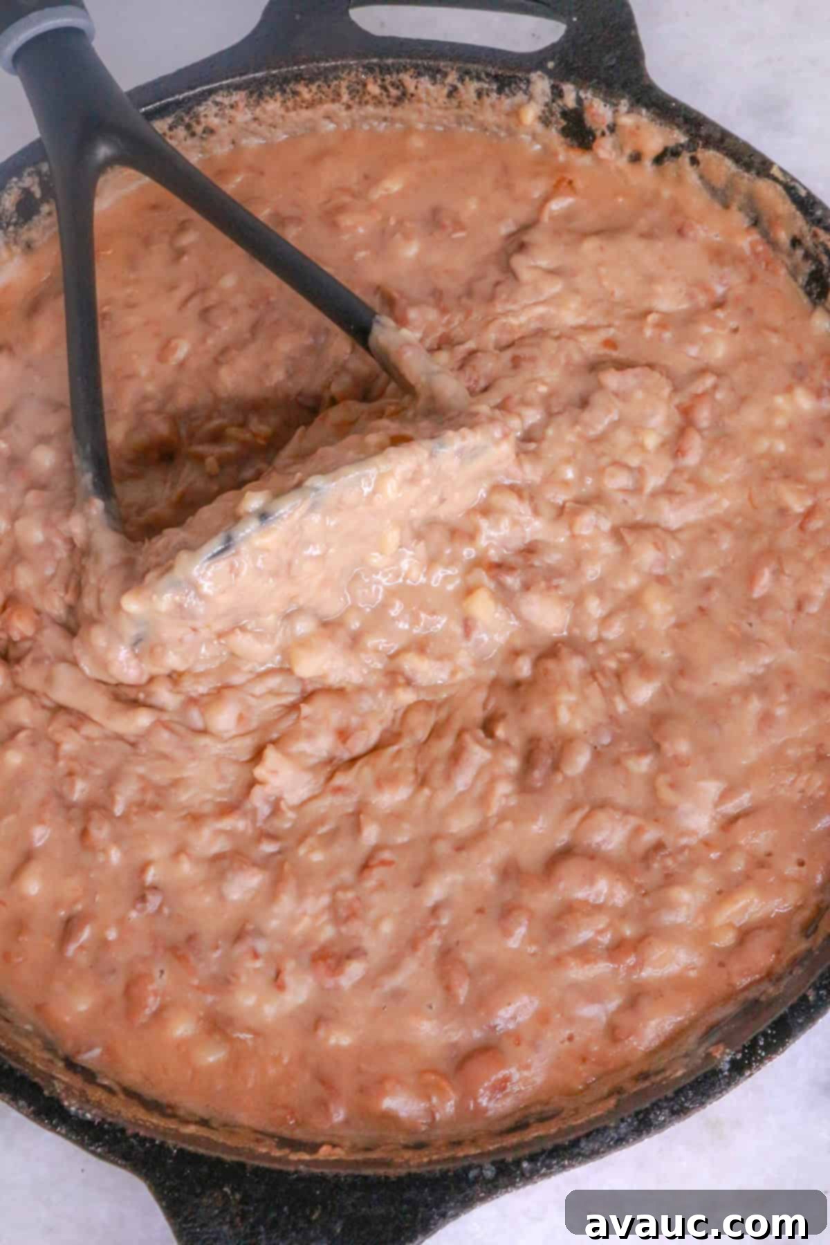 Homemade Mexican Molletes 4 Mashing refried beans in a skillet for molletes